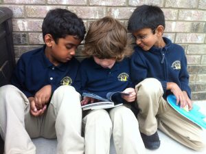 Three preschool aged boys reading a book.