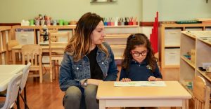 montessori teacher showing a girl how to read